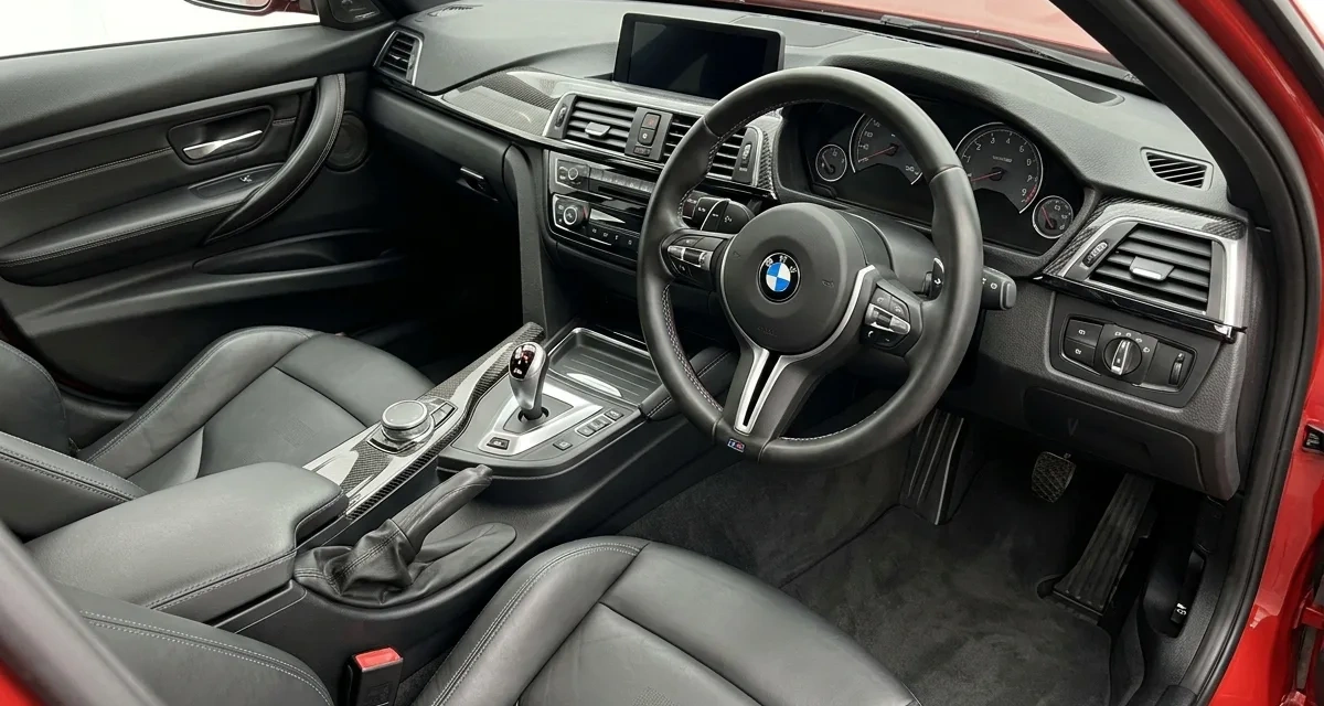 Interior of a red BMW M3 showing the steering wheel and centre console