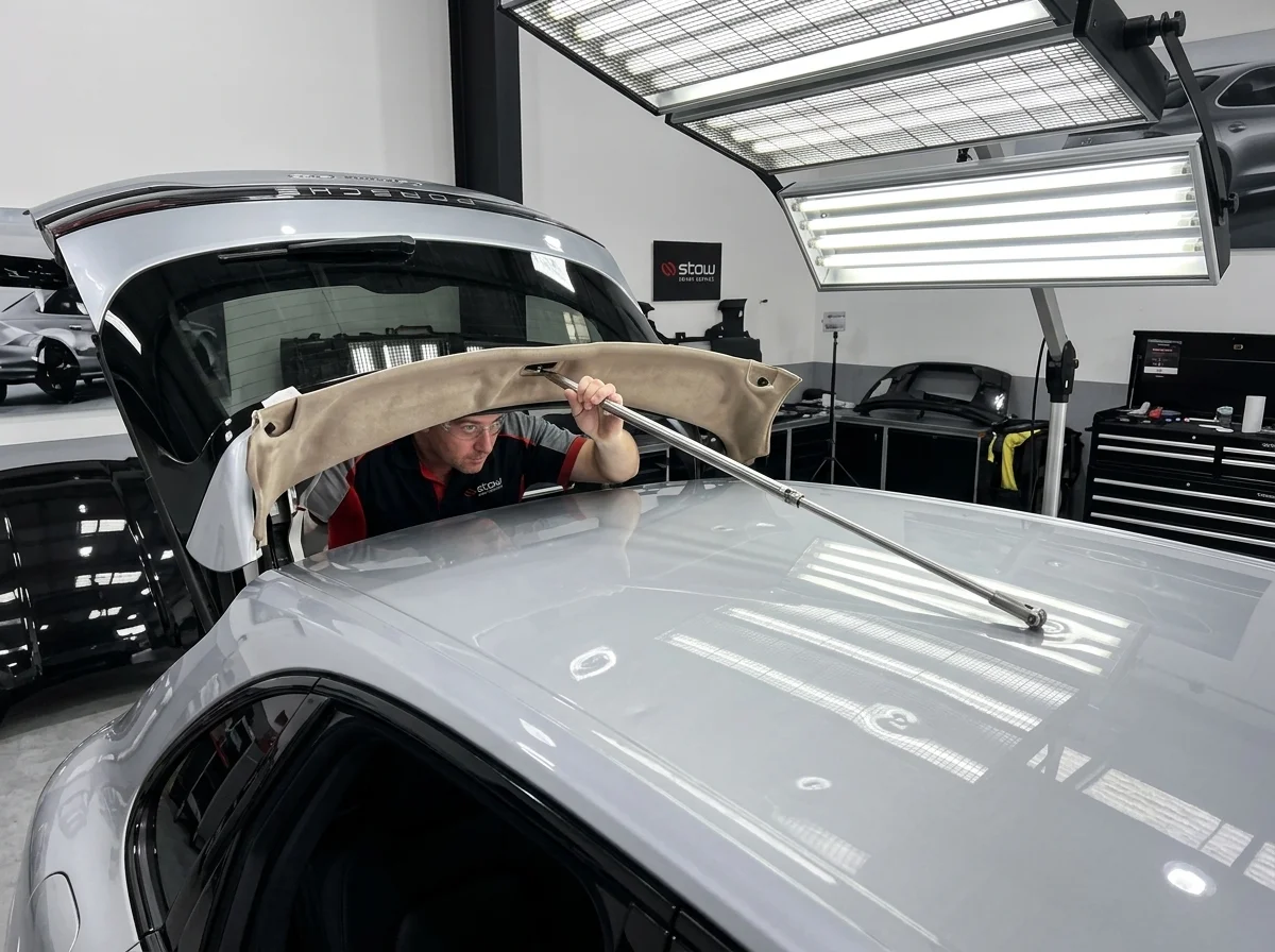 Technician using long steel PDR roof rod through tailgate cavity at Stow Smash Repairs