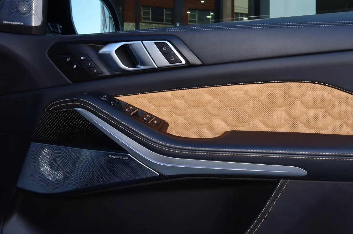 Close-up of a prestige vehicle's quilted leather door trim and speaker