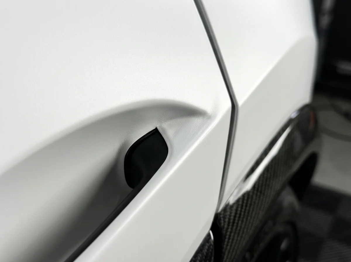 Close-up of seamless tucked vinyl wrap edges around a door handle recess at Stow Smash Repairs